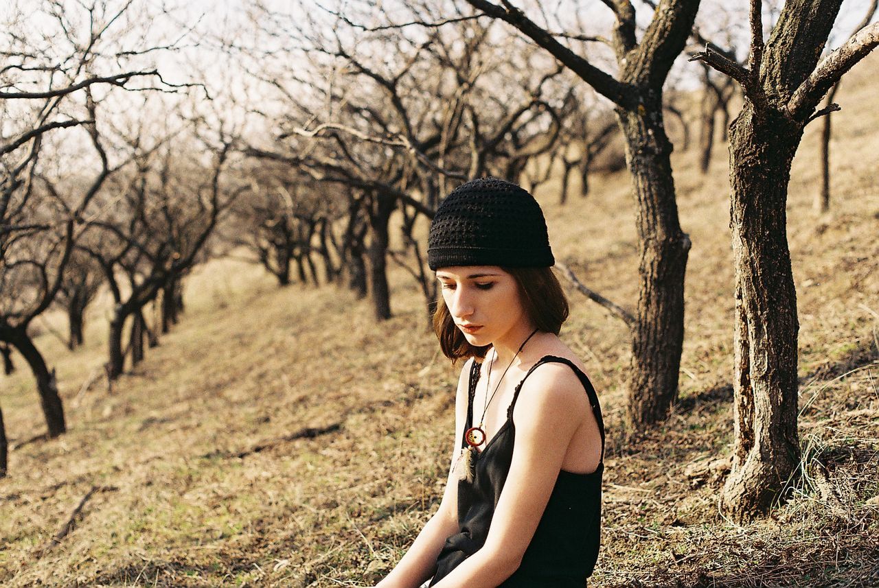 Thoughtful young woman looking away while sitting in forest