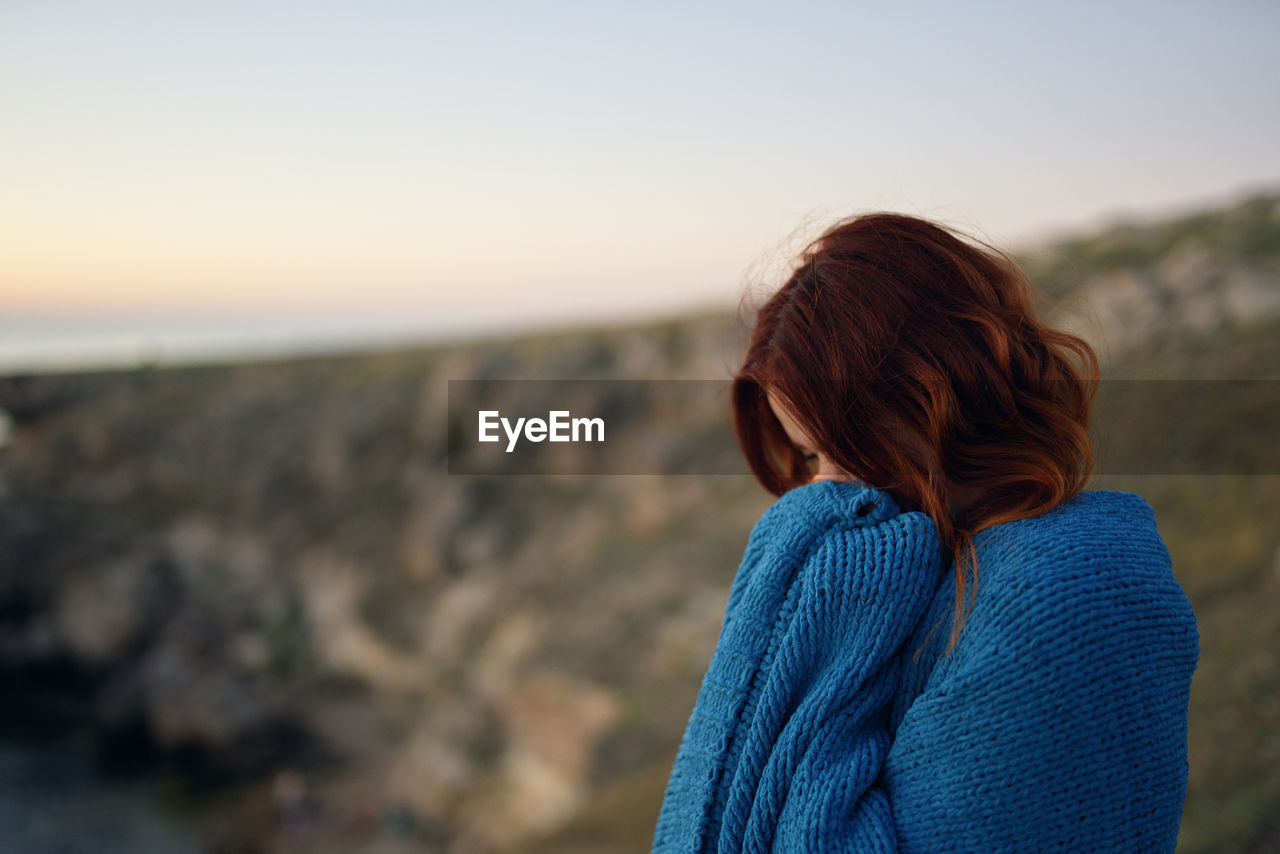 REAR VIEW OF WOMAN LOOKING AT VIEW OF SUNSET