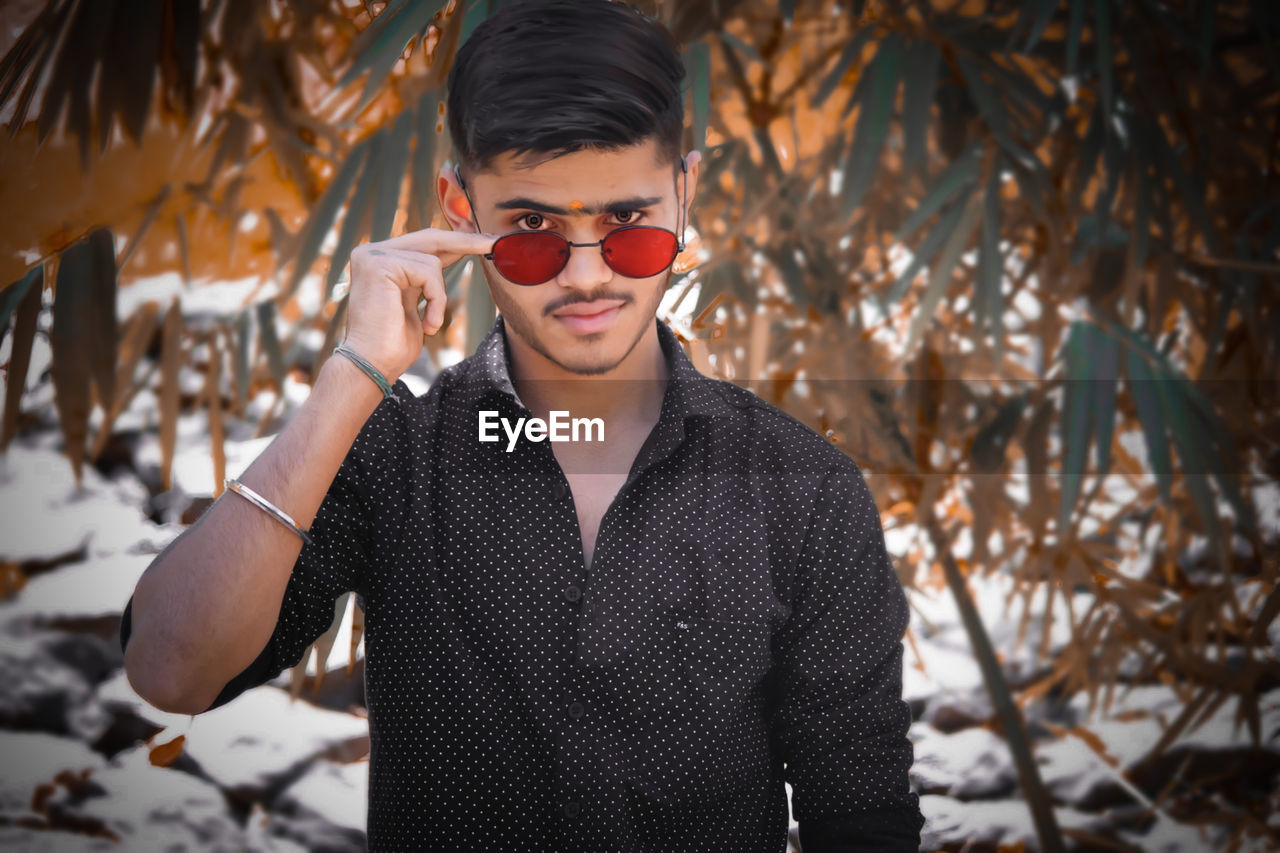 Portrait of young man wearing sunglasses standing outdoors