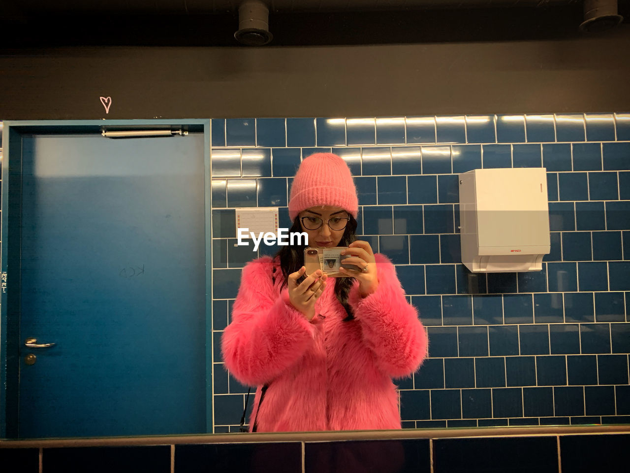 Woman photographing with smart phone while standing in bathroom