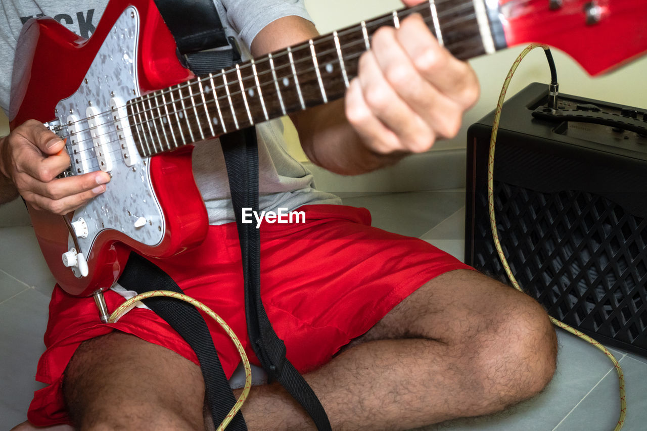 MIDSECTION OF MAN PLAYING GUITAR AT MUSIC CONCERT