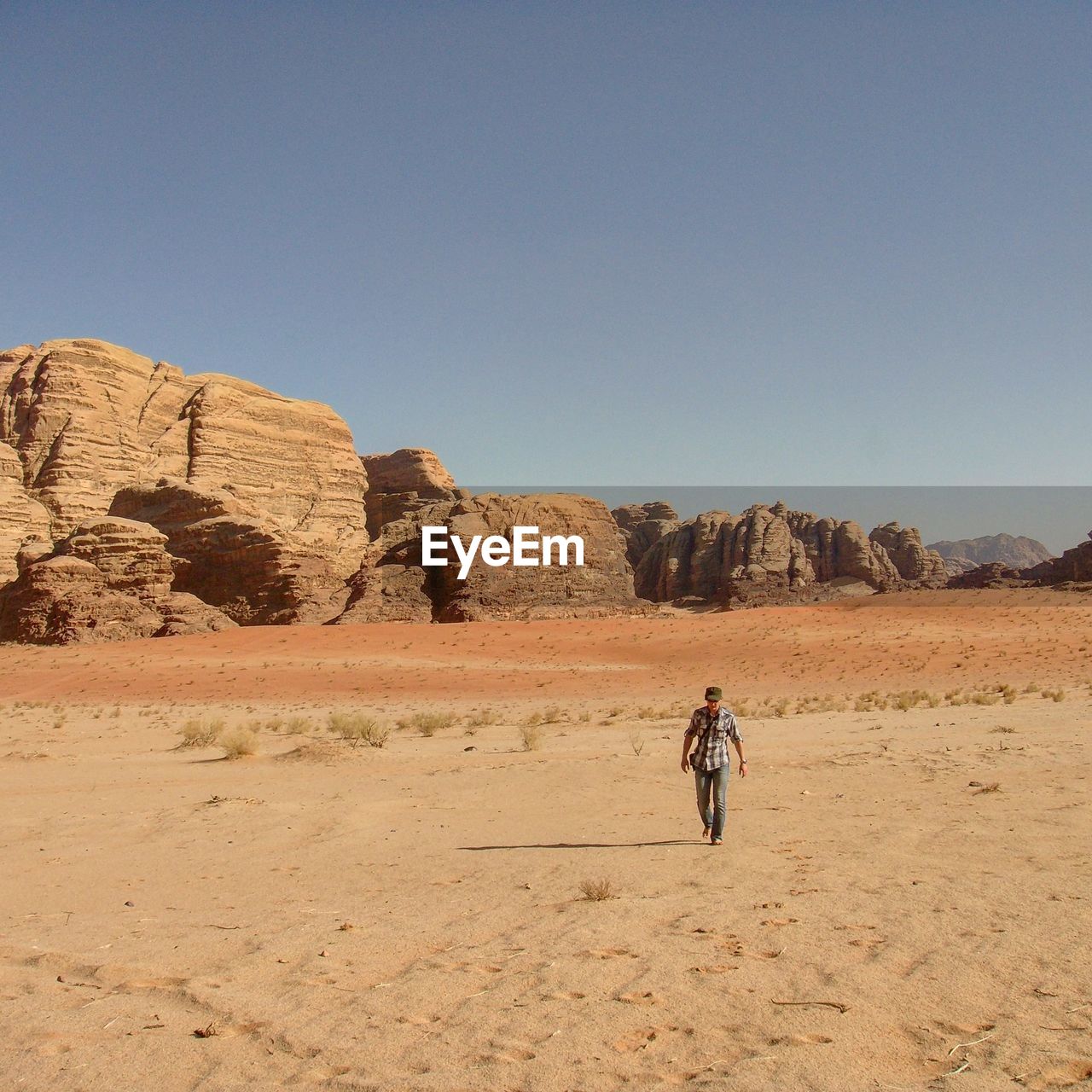 People on rock formations in desert against clear sky