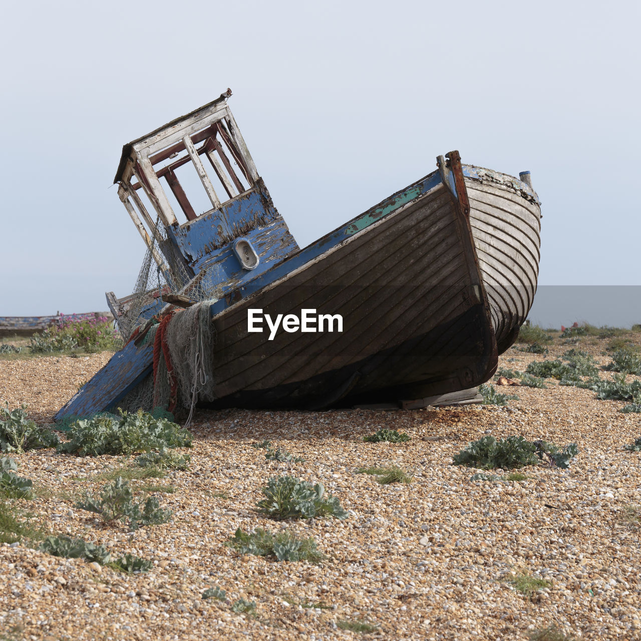 Abandoned boat on land against sky