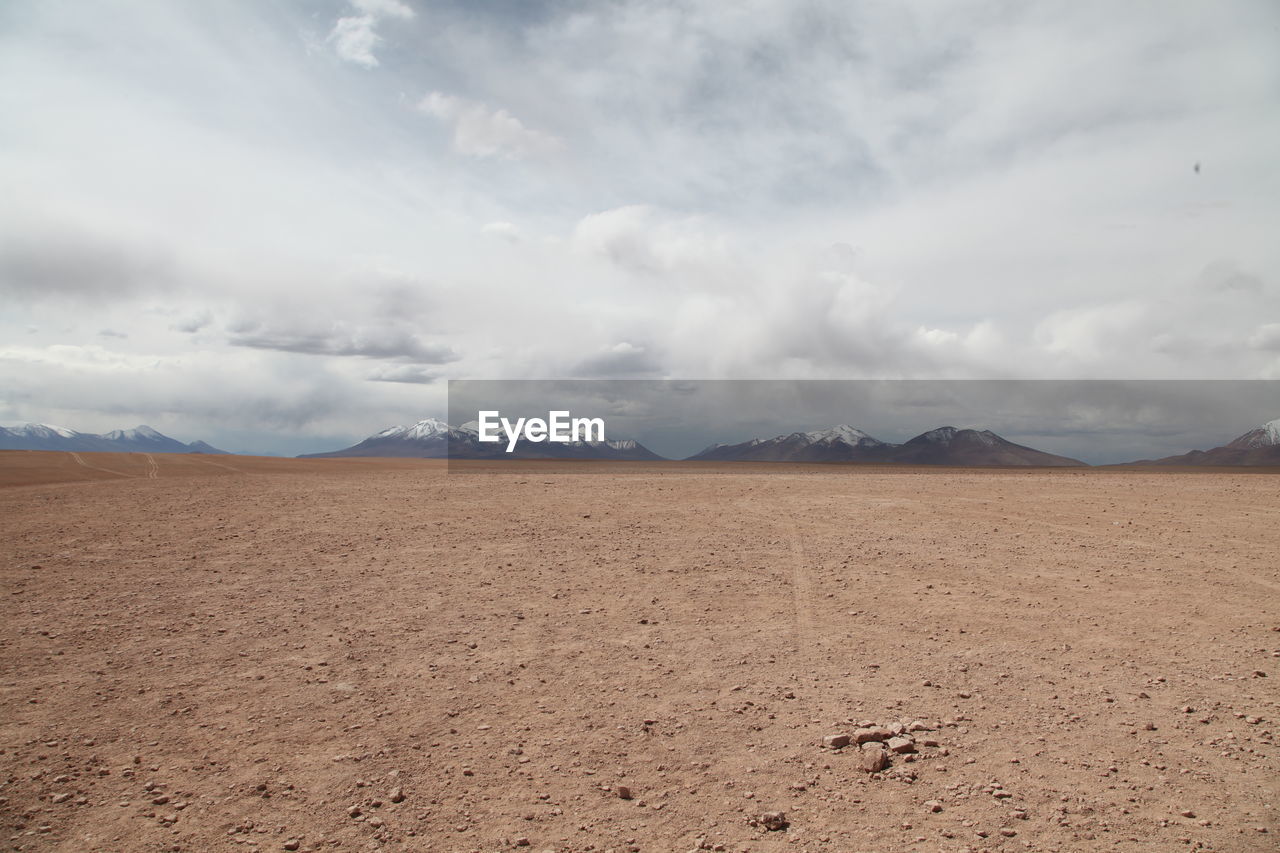 Tranquil view of desert landscape against cloudy sky