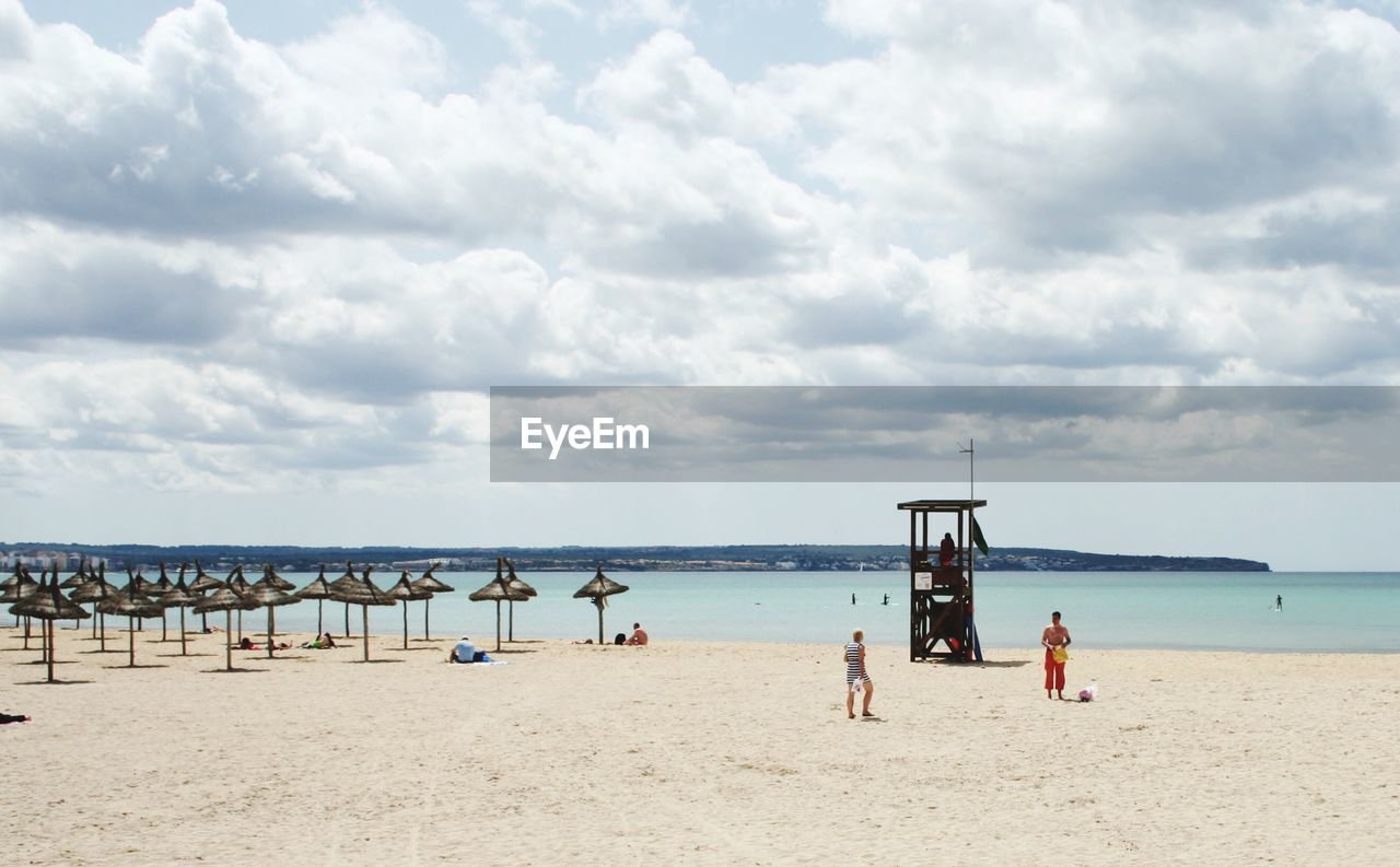 People at beach against sky