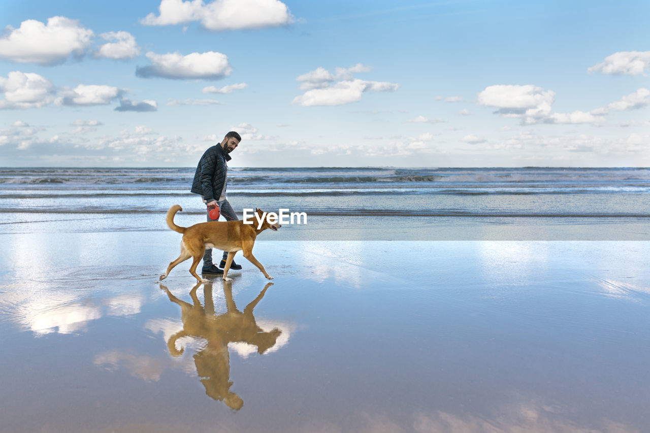 Man walking on the beach with his dog