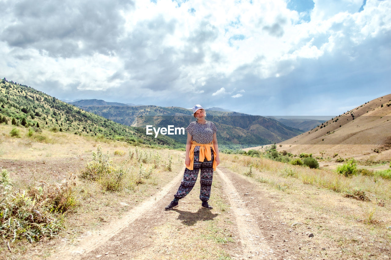 landscape, sky, cloud, mountain, nature, full length, adult, environment, travel, leisure activity, road, scenics - nature, walking, hiking, activity, men, adventure, beauty in nature, holiday, footpath, mountain range, lifestyles, ridge, vacation, trail, sunlight, one person, day, transportation, trip, exploration, travel destinations, dirt road, journey, non-urban scene, backpack, outdoors, land, rear view, rural scene, remote, dirt, sports, on the move, motion, backpacking, person, tourism, recreation, the way forward, copy space, women, tranquil scene, exercising, clothing, casual clothing