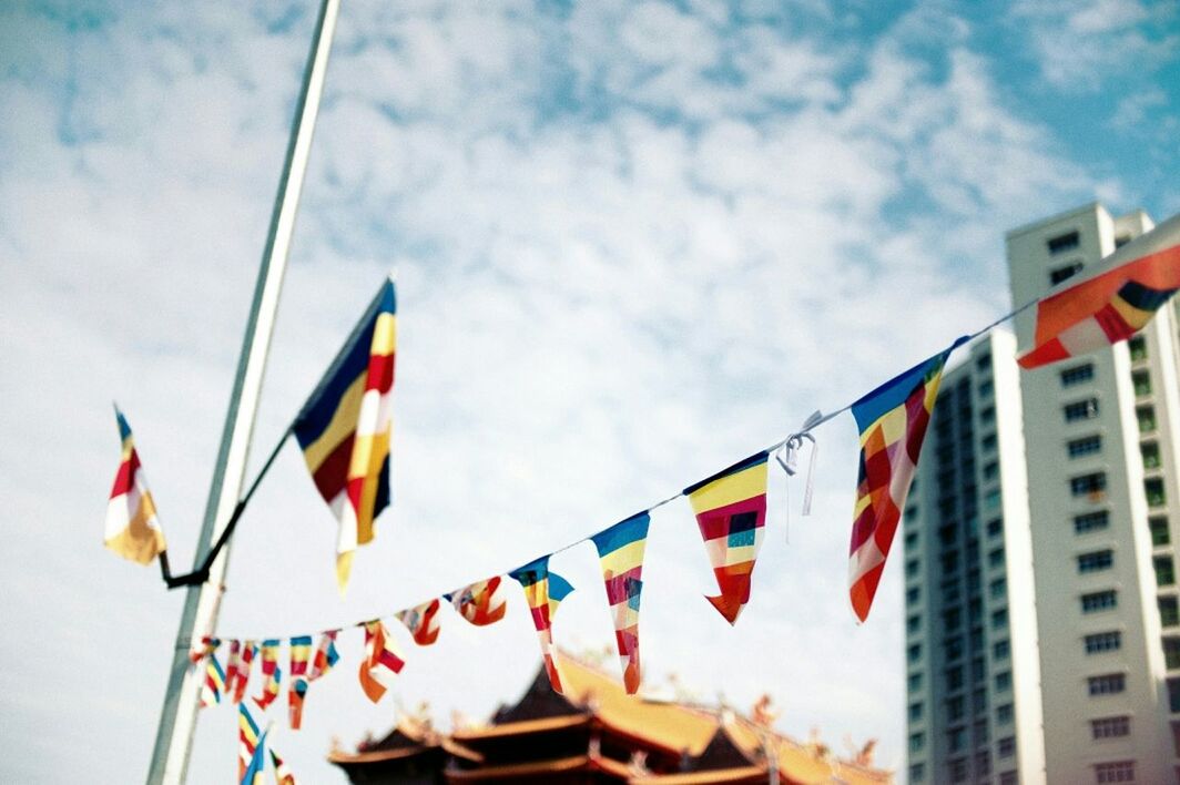 Low angle view of multi colored prayer flags hanging against sky