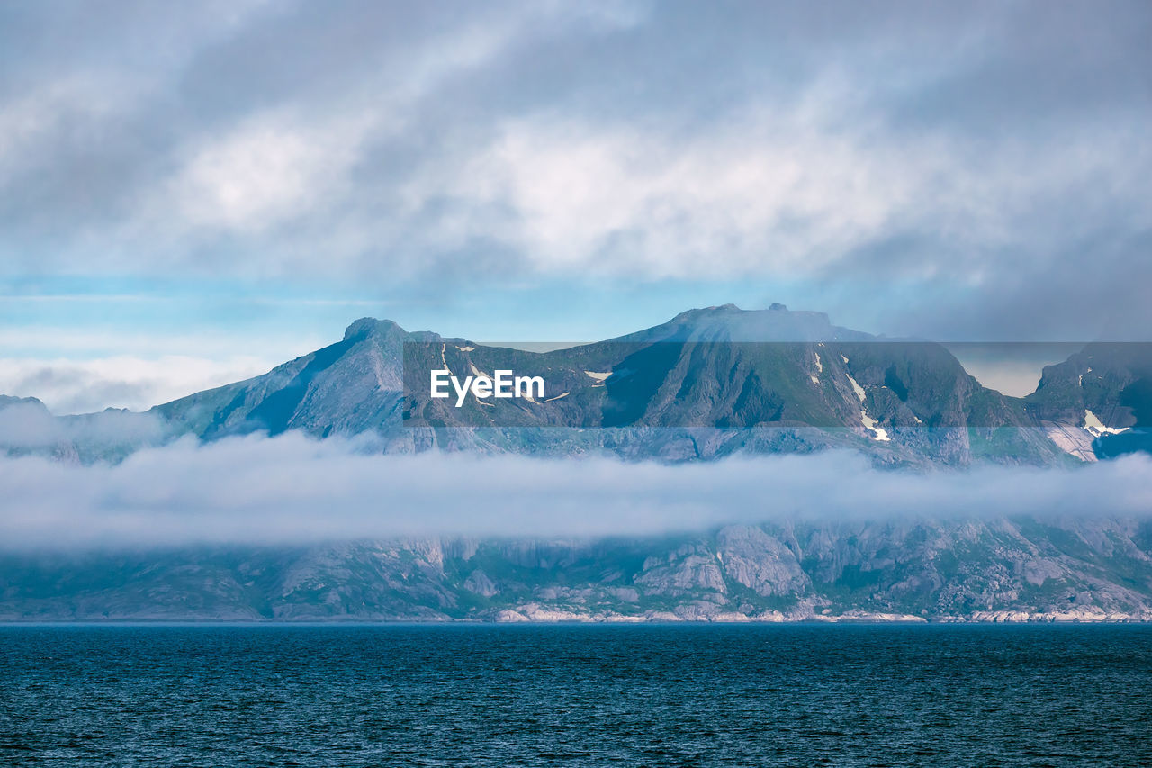 Scenic view of sea and snowcapped mountains against sky