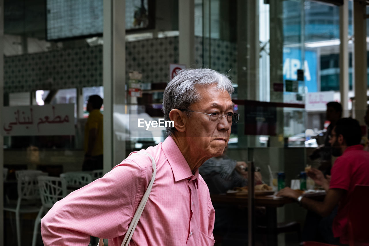 Thoughtful man standing against restaurant in city