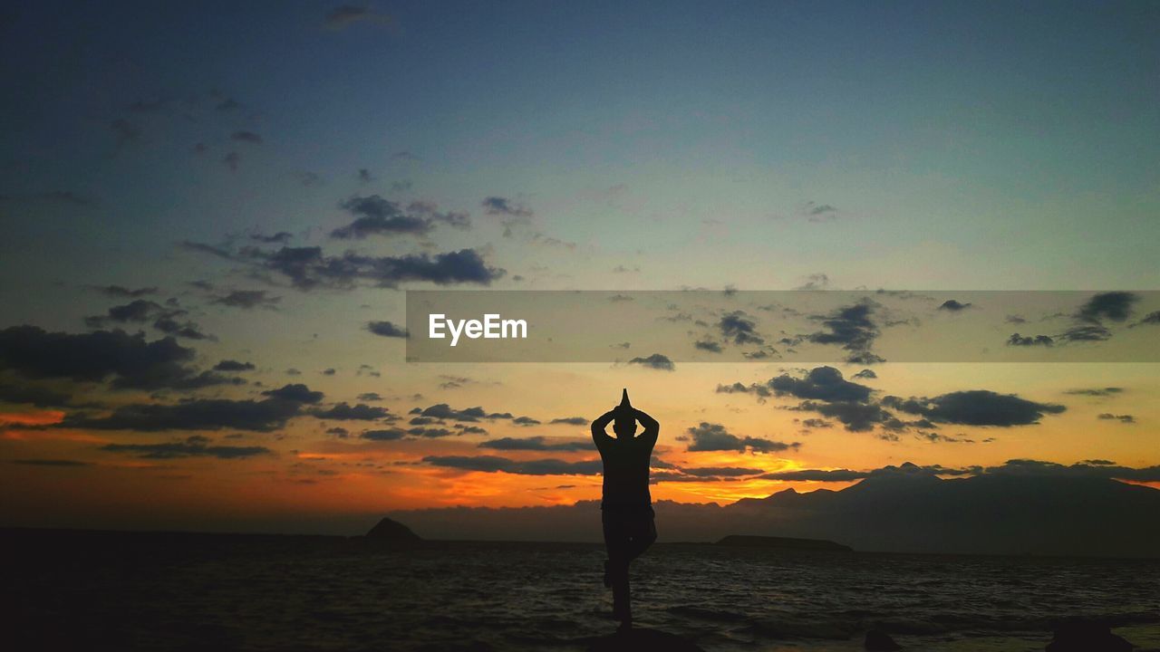 SILHOUETTE WOMAN STANDING BY SEA AGAINST SKY DURING SUNSET