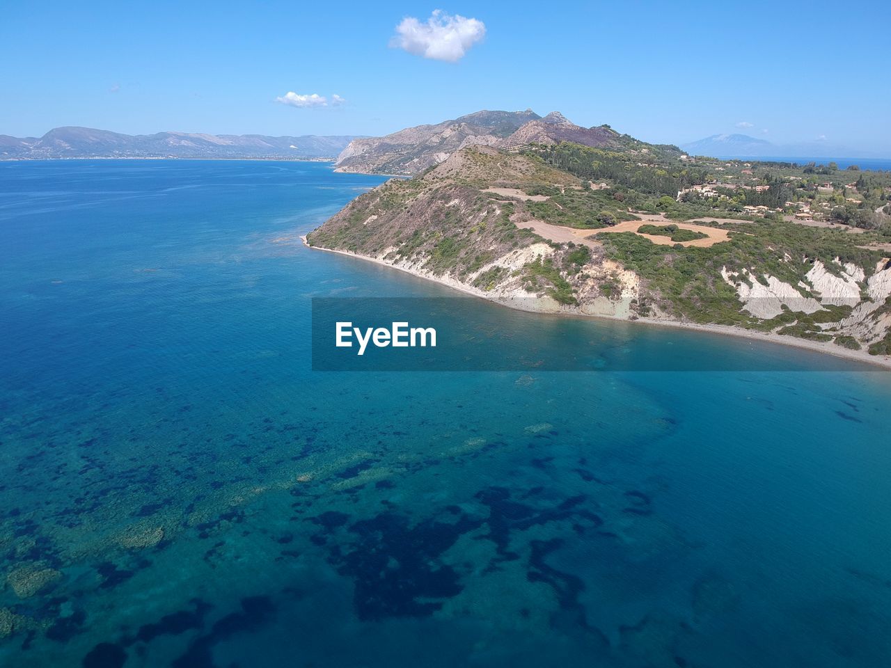 Aerial view of sea and mountains against blue sky