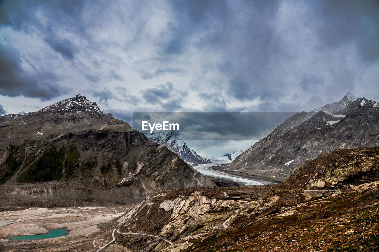 Scenic view of rocky mountains against cloudy sky at drang drung glacier