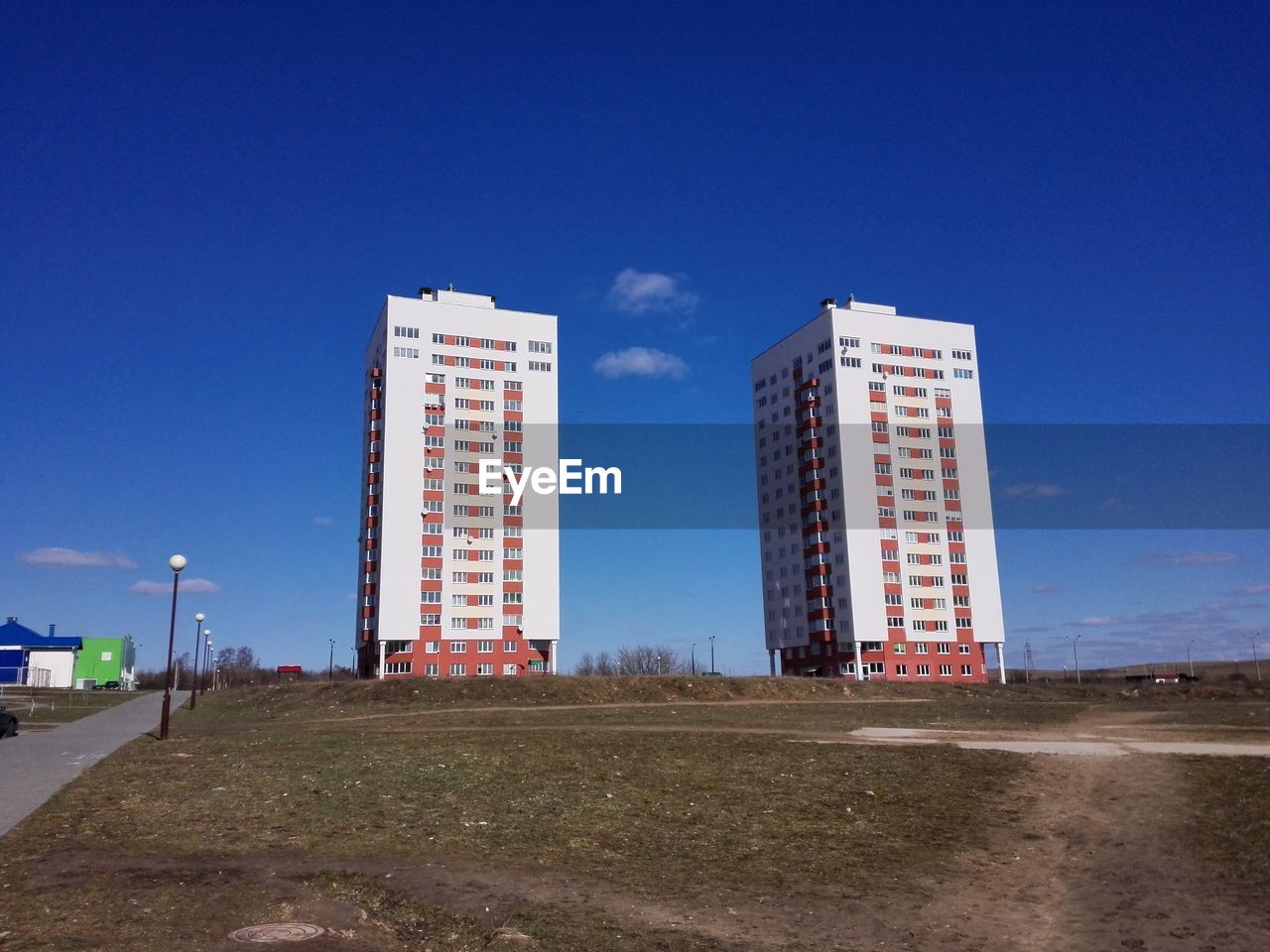 Field by building in city against sky