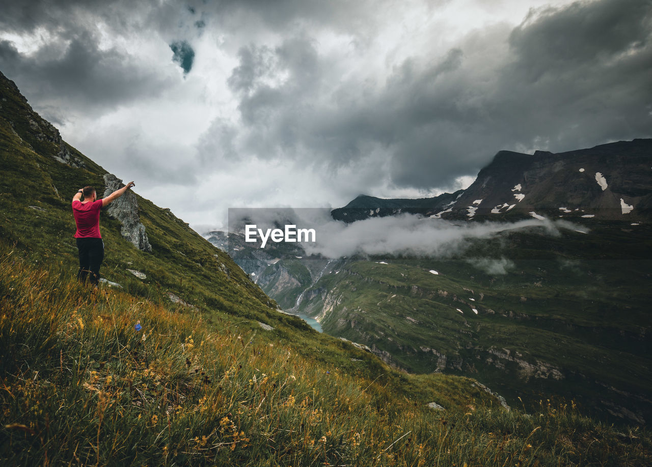 Rear view of man standing on mountain against sky