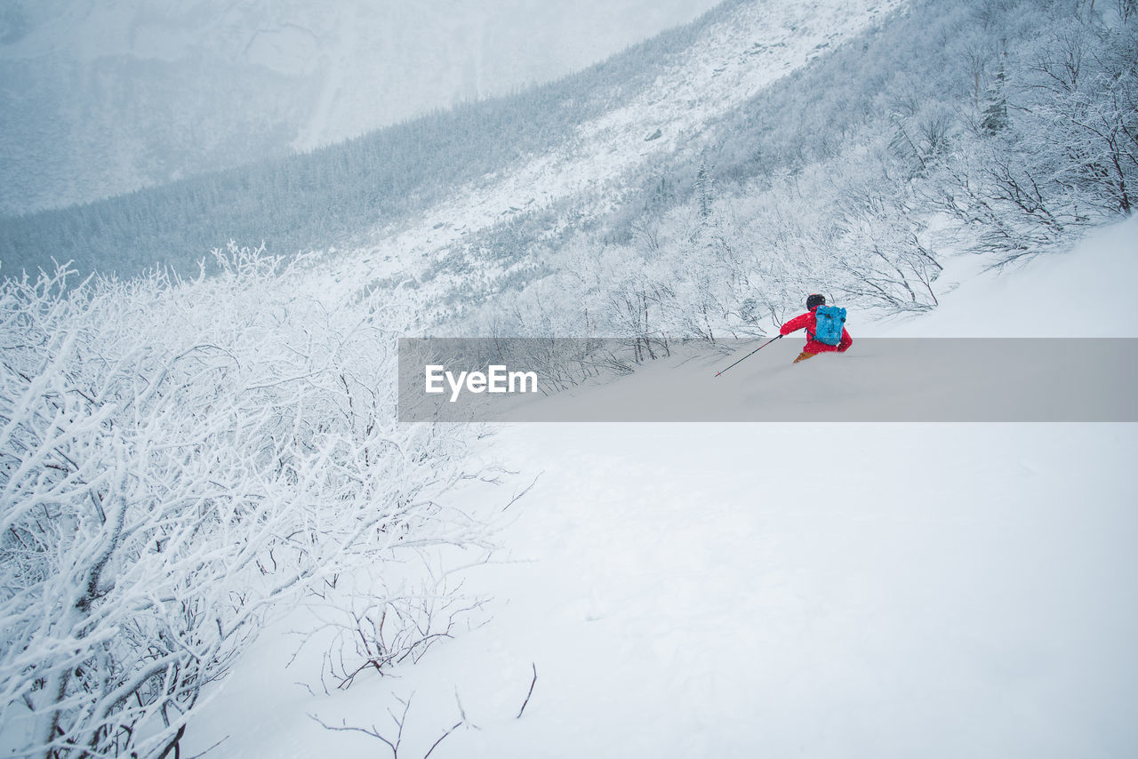 Man skiing in deep snow in the alpine during a snowstorm in maine