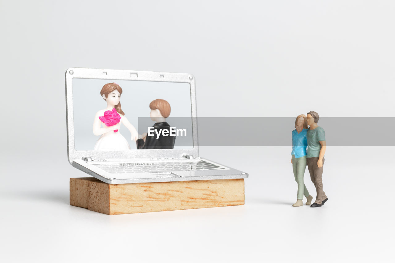 adult, studio shot, women, men, indoors, business, person, female, copy space, white background, full length, clothing, toy, two people, communication, technology, cartoon, human representation, childhood, child, standing, business finance and industry, togetherness, computer, wireless technology