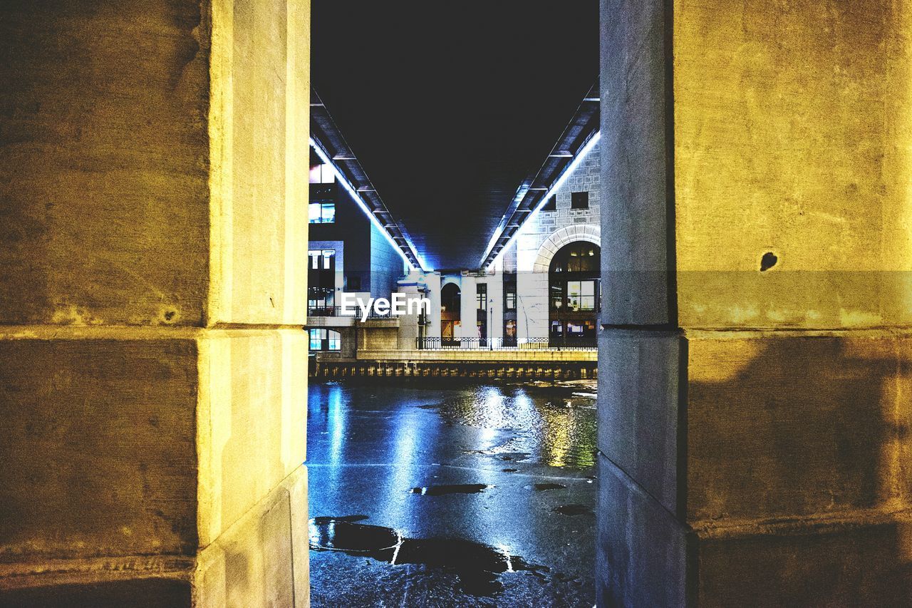 Wet road below bridge at night