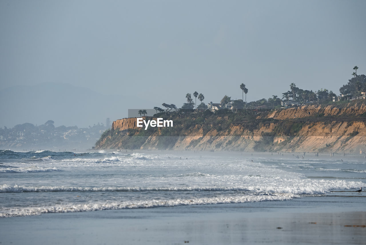 Scenic view of waves splashing in sea by rocky cliff at san diego