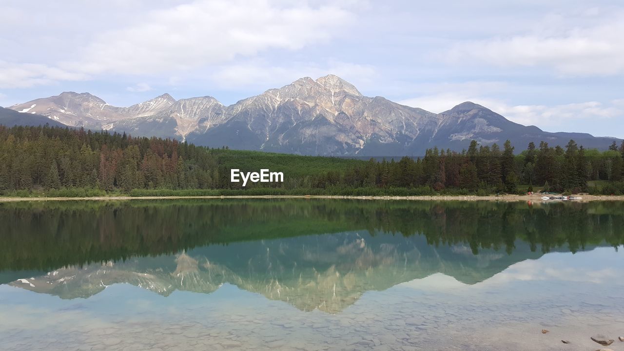 Reflection of trees and mountains in river against sky