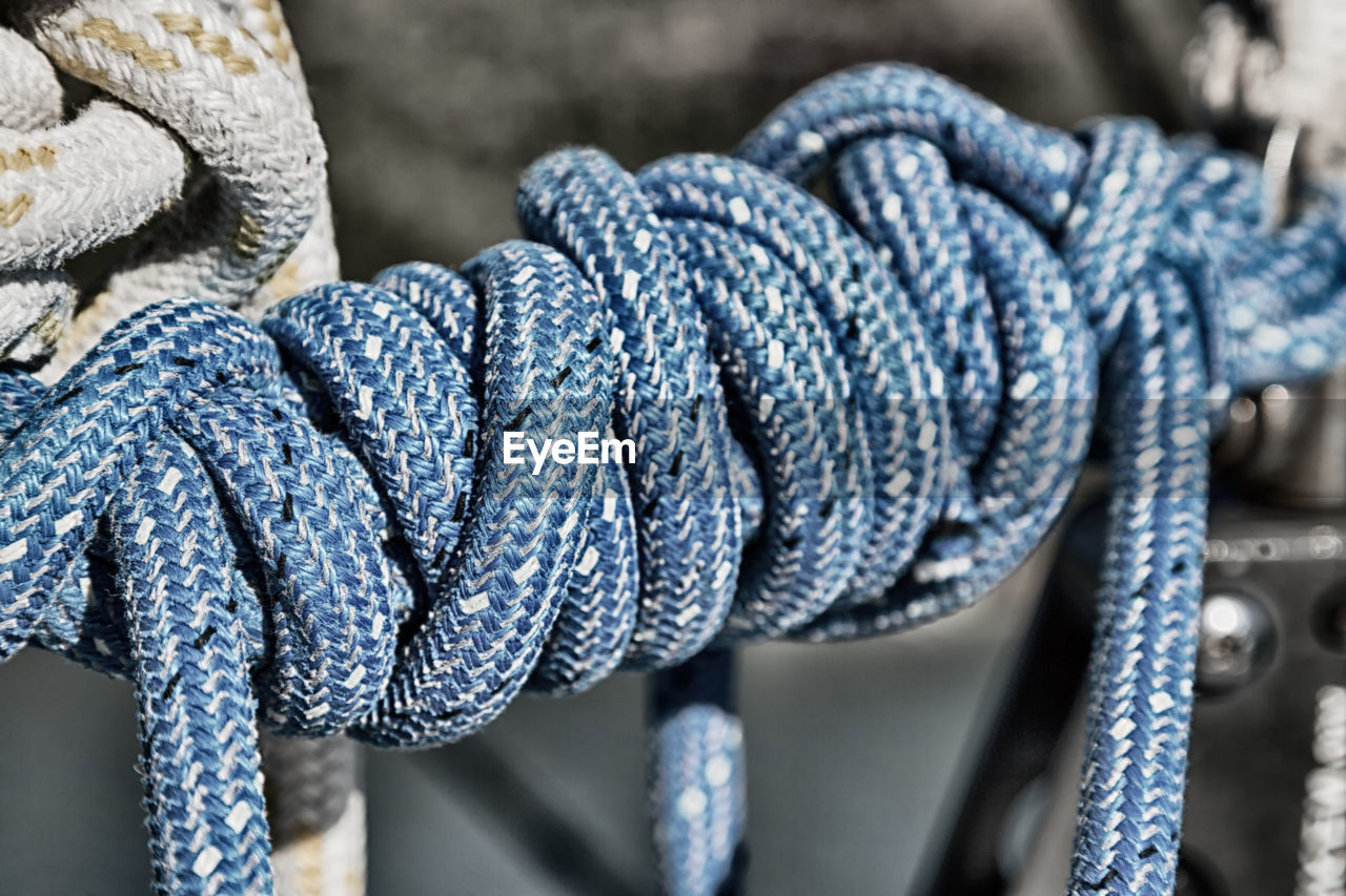 CLOSE-UP OF ROPE TIED ON METAL OUTDOORS