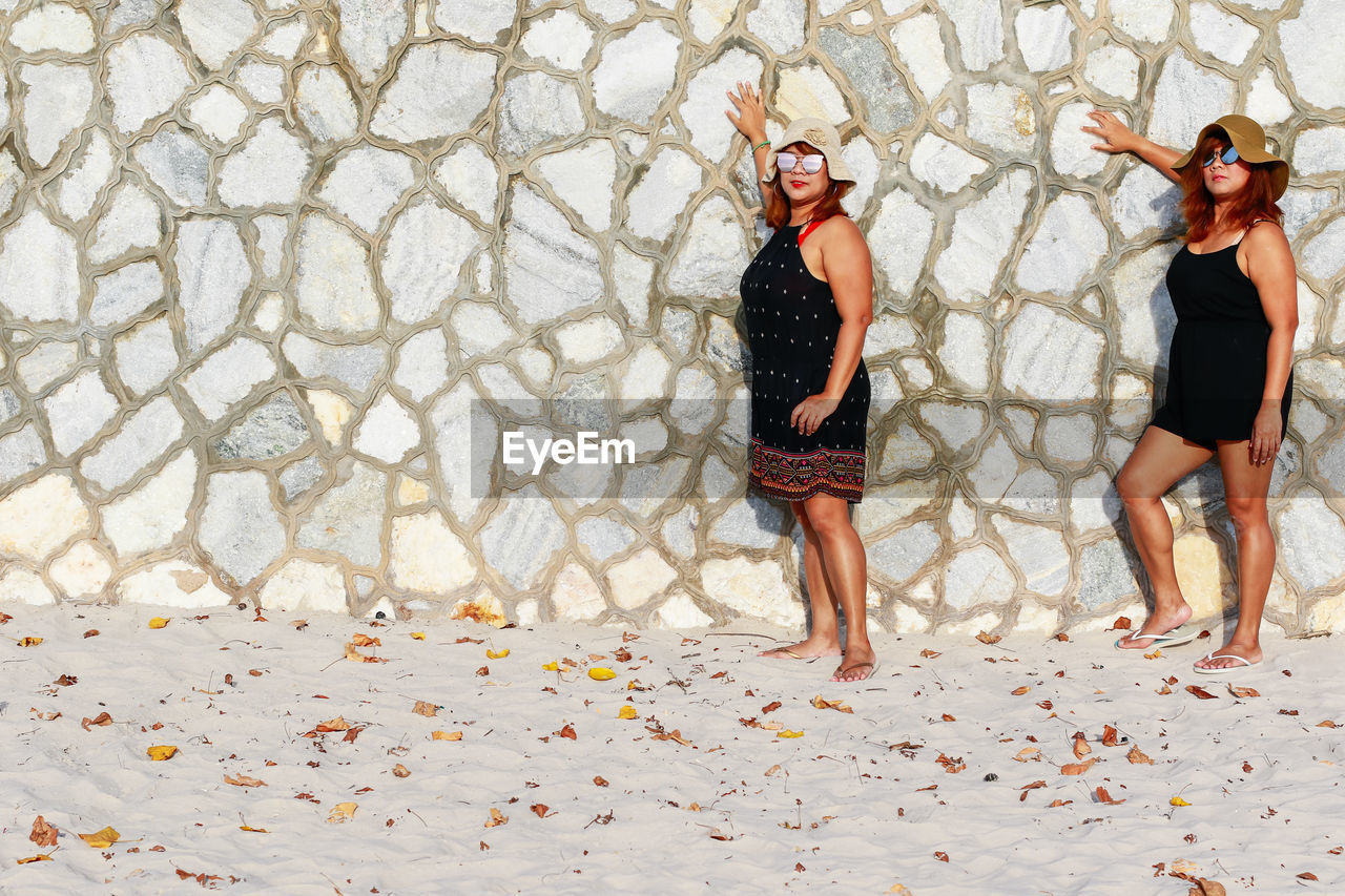 FULL LENGTH OF WOMEN STANDING ON COBBLESTONE