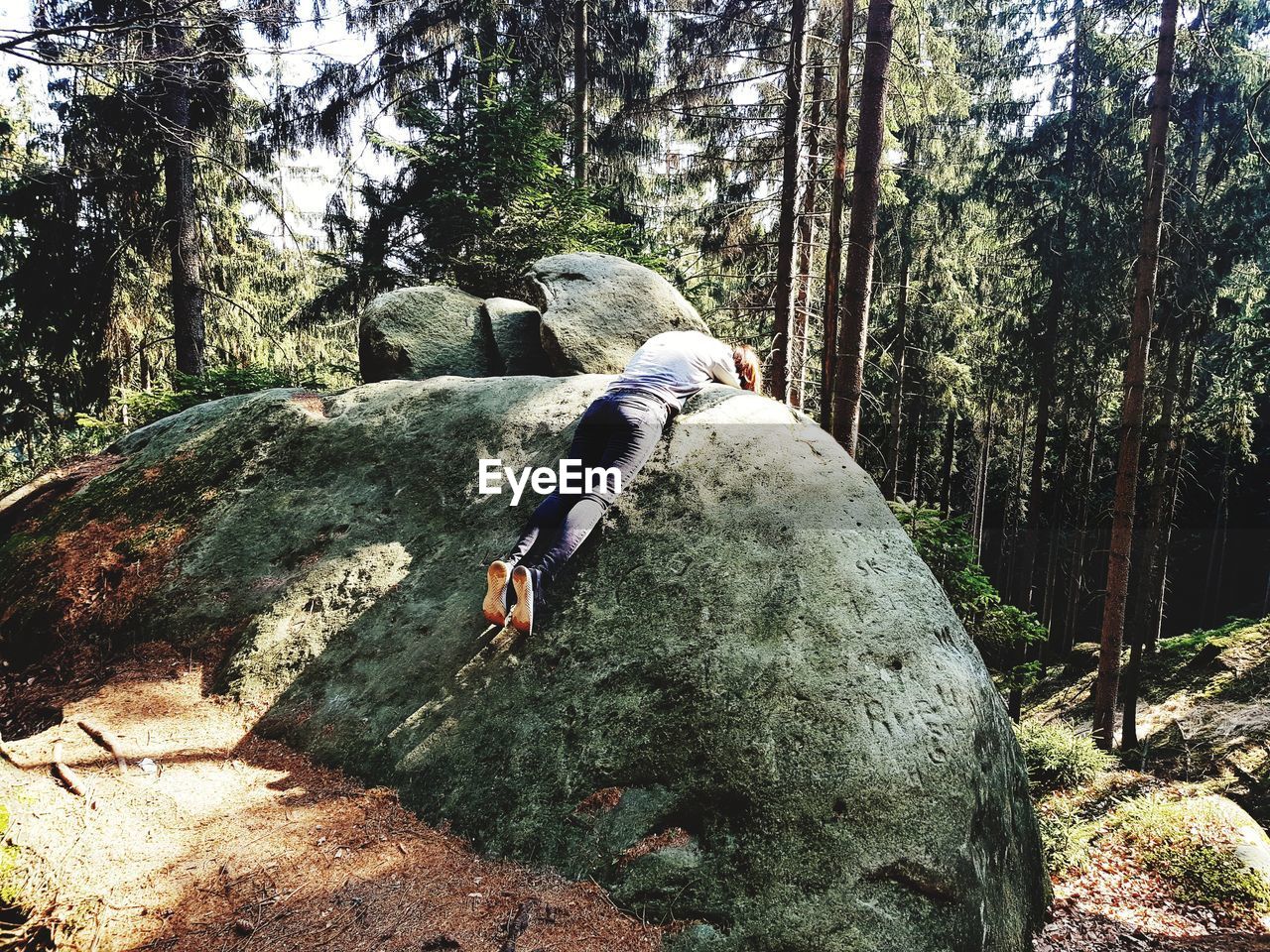 Woman relaxing on rock in forest