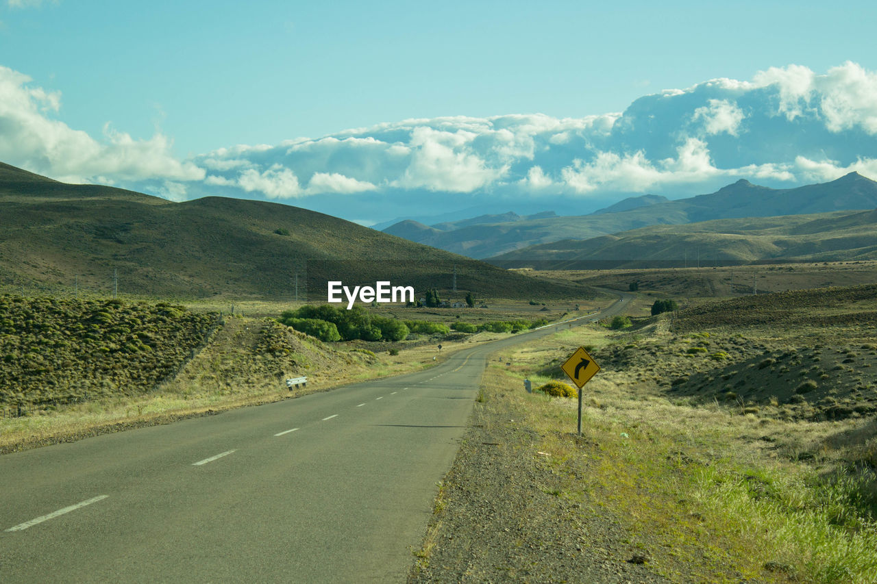 Road leading towards mountains against sky