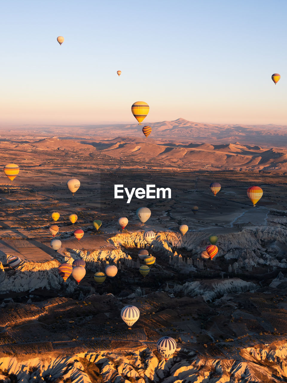 HOT AIR BALLOON FLYING OVER LANDSCAPE AGAINST SKY