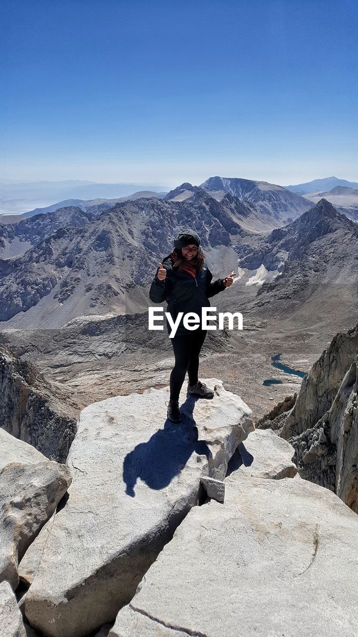 Full length of woman standing on cliff against mountain range