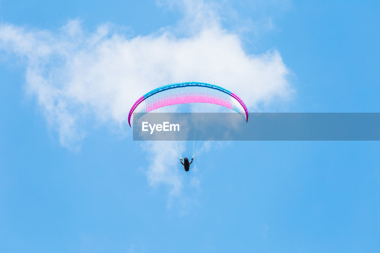 Low angle view of person paragliding against blue sky