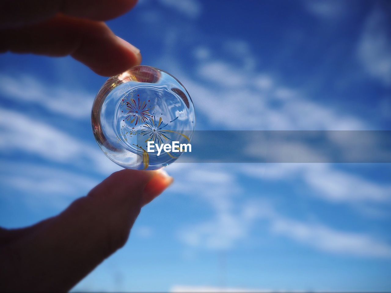 Close-up of hand holding glass against sky