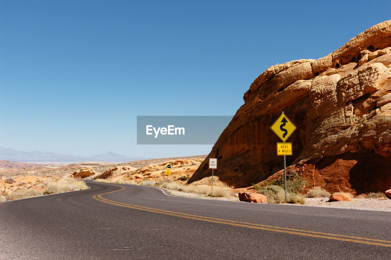 Road sign in desert against clear sky