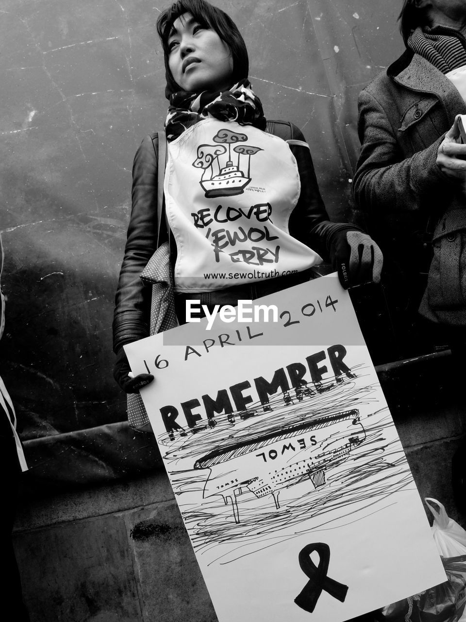 Woman holding poster while standing against wall