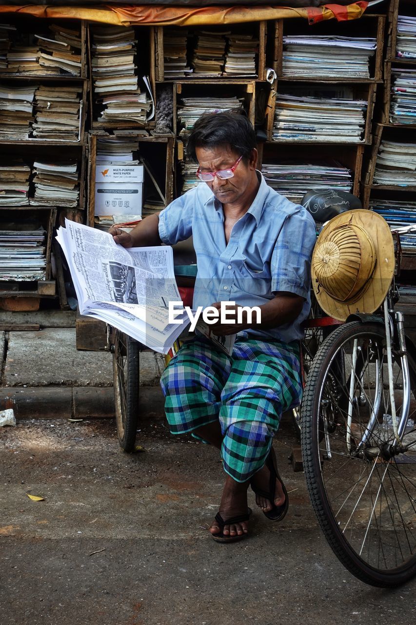 Full length of man reading newspaper at market