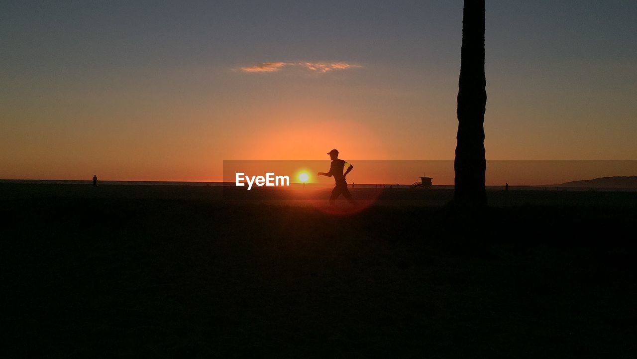 SILHOUETTE MAN STANDING ON LANDSCAPE AT SUNSET