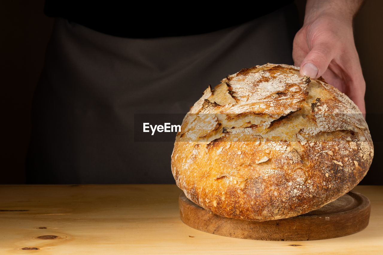 midsection of person holding bread on table