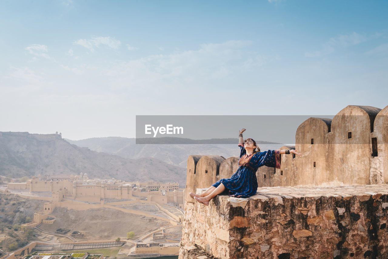 Woman sitting at fort against mountains