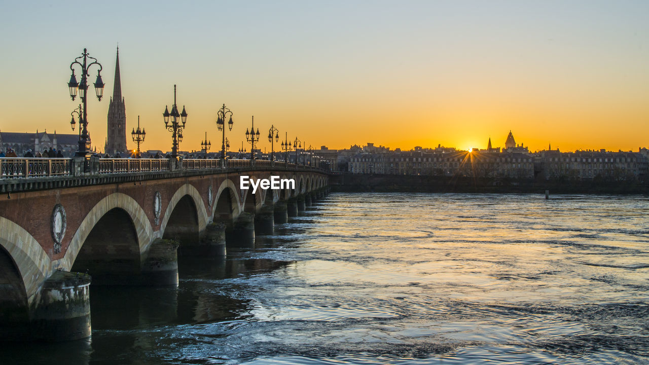 Bridge over river against sky during sunset