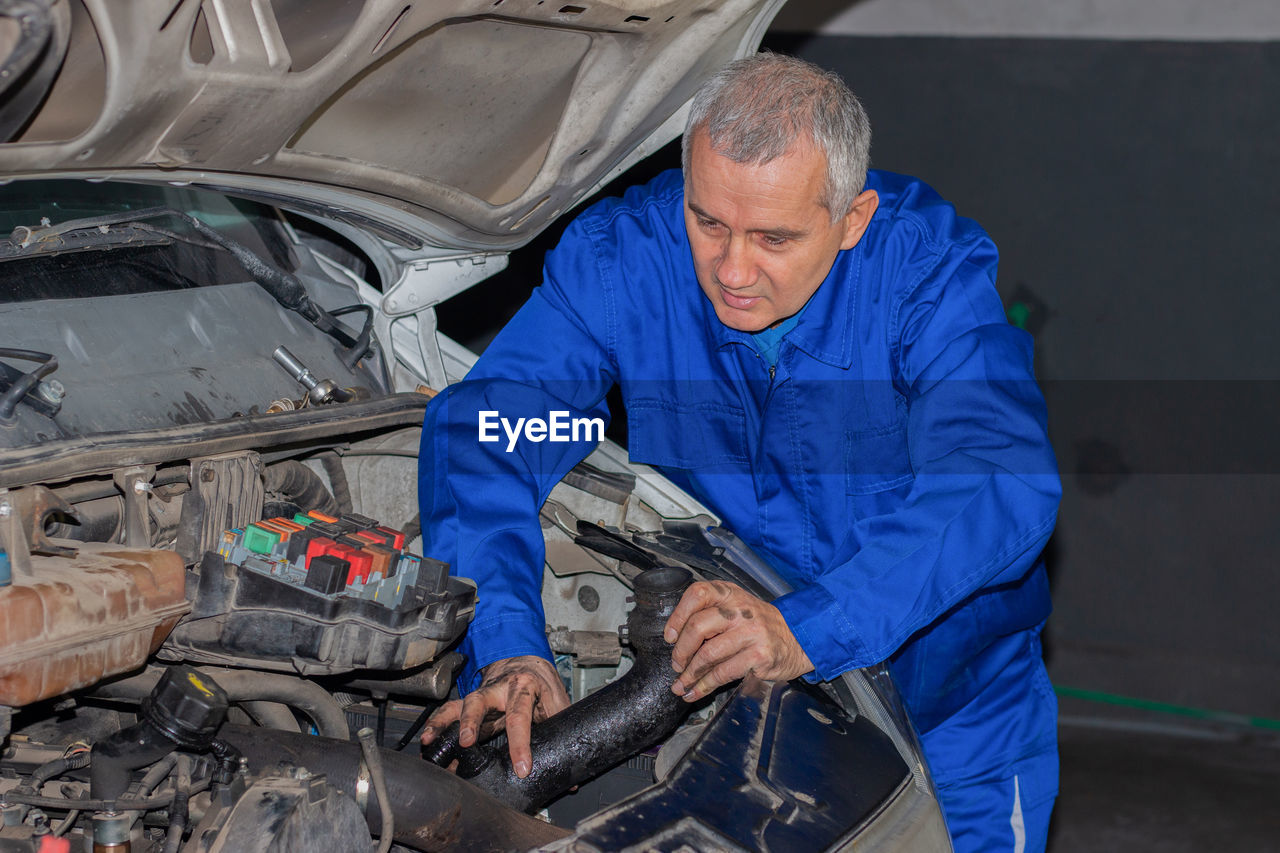 Senior experienced mechanic repairing a car at garage