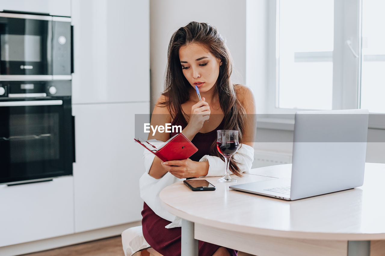 FULL LENGTH OF WOMAN USING PHONE WHILE SITTING IN RESTAURANT