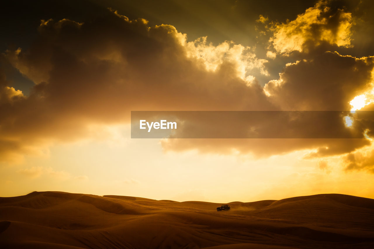 Scenic view of dramatic sky over desert landscape with car