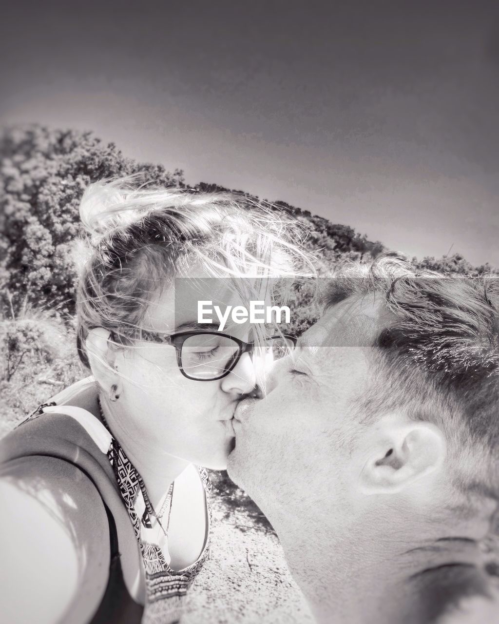 Tilt image of couple kissing against sky