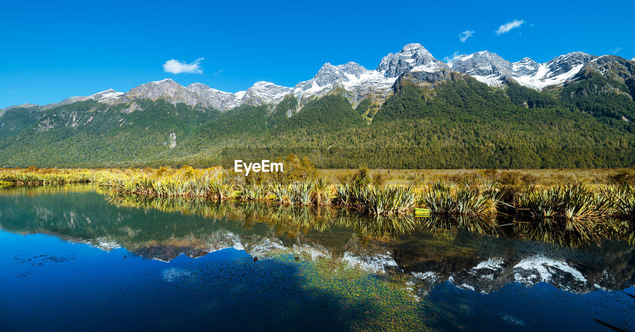 Scenic view of lake and mountains against blue sky