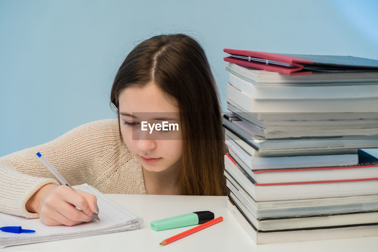 Teenage girl writing on book at home