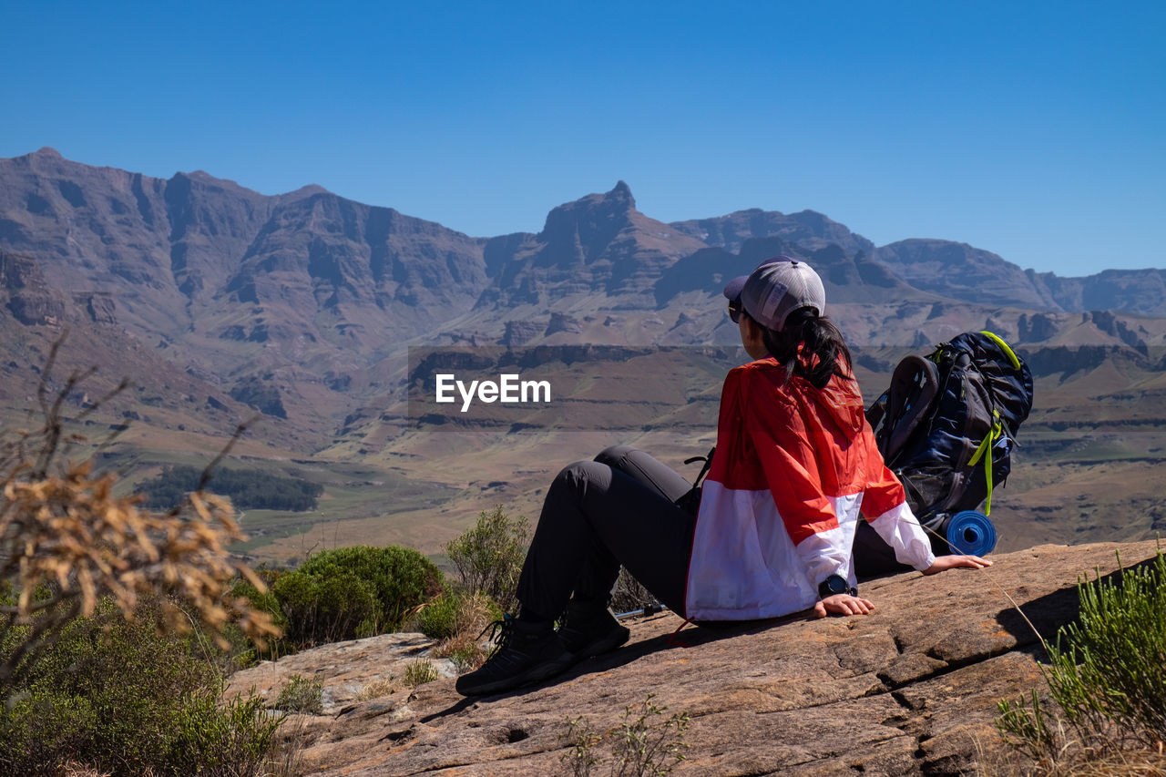 Rear view of woman on mountain against sky looking at mountain peak ahead
