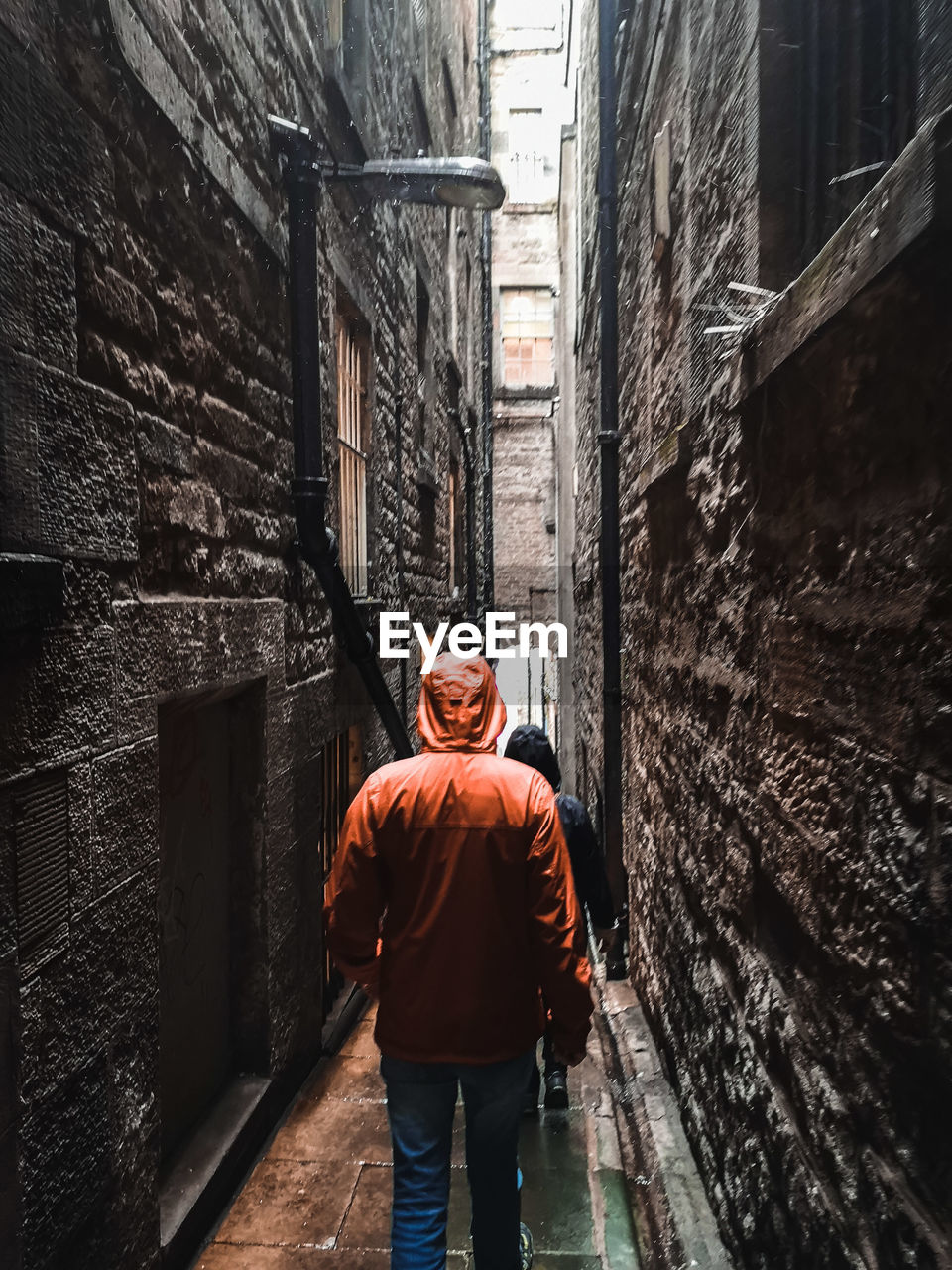 Rear view of man walking in narrow alley