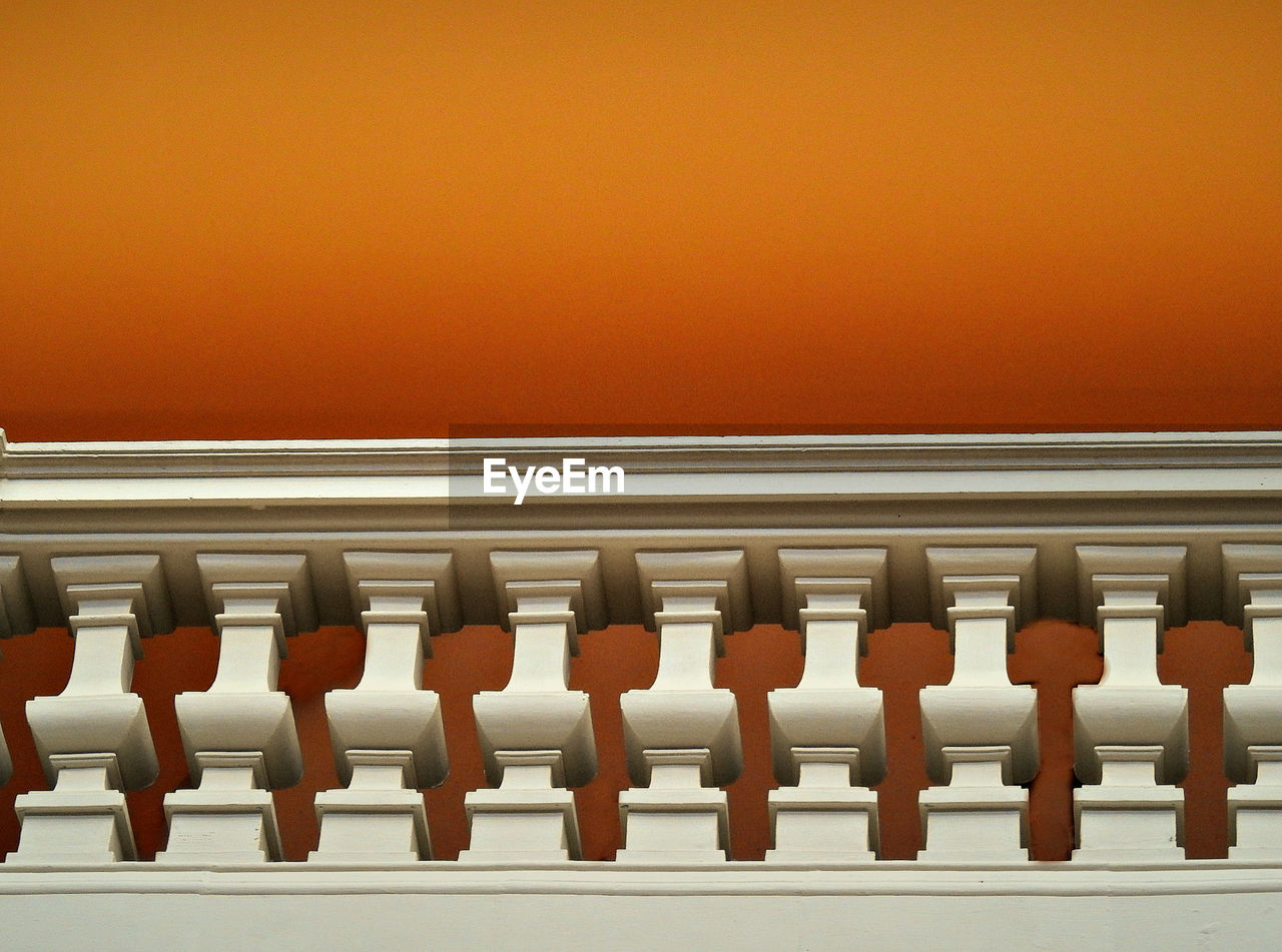 Low angle view of railing against orange background