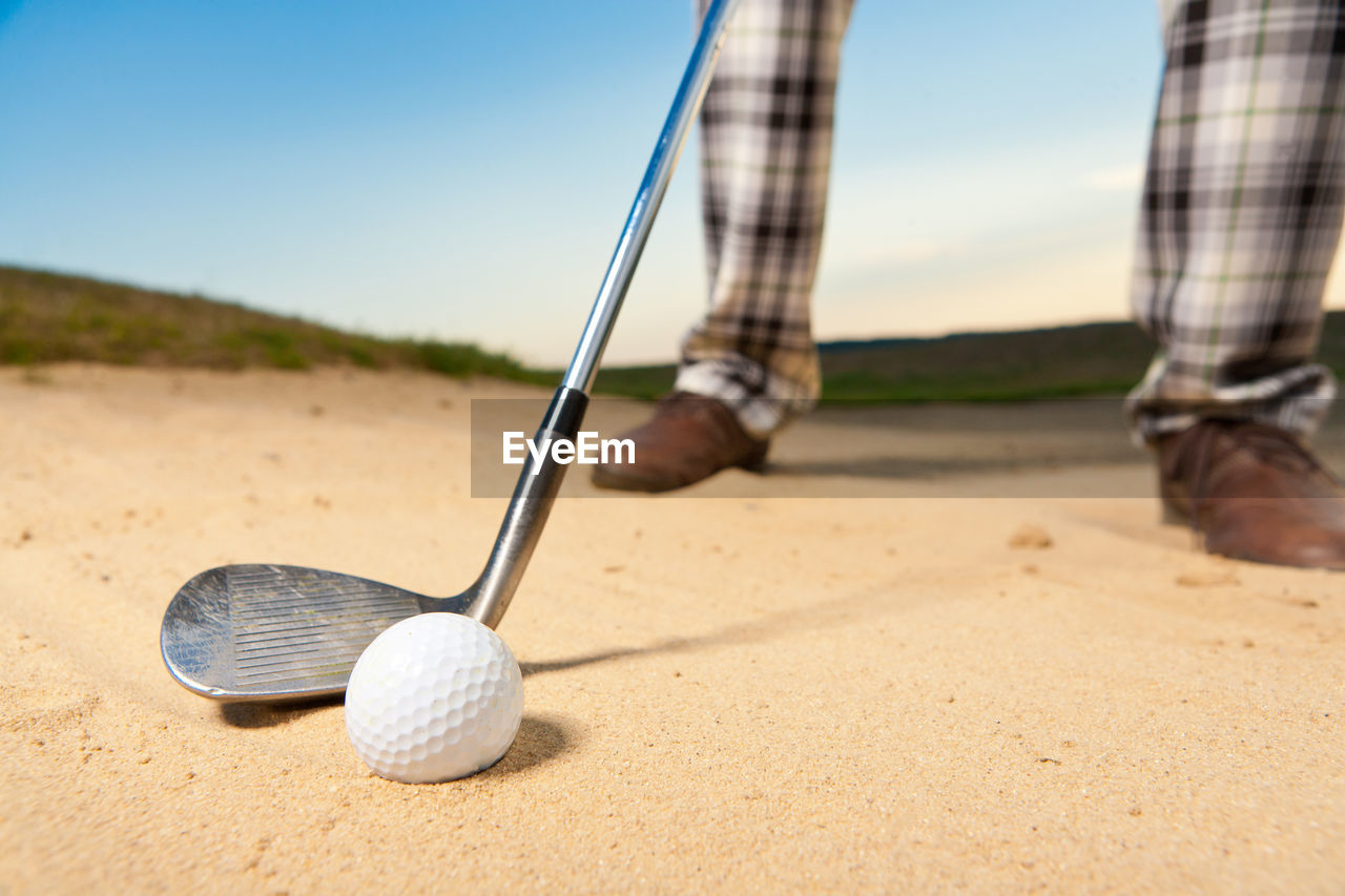 Low section of person playing golf on sand