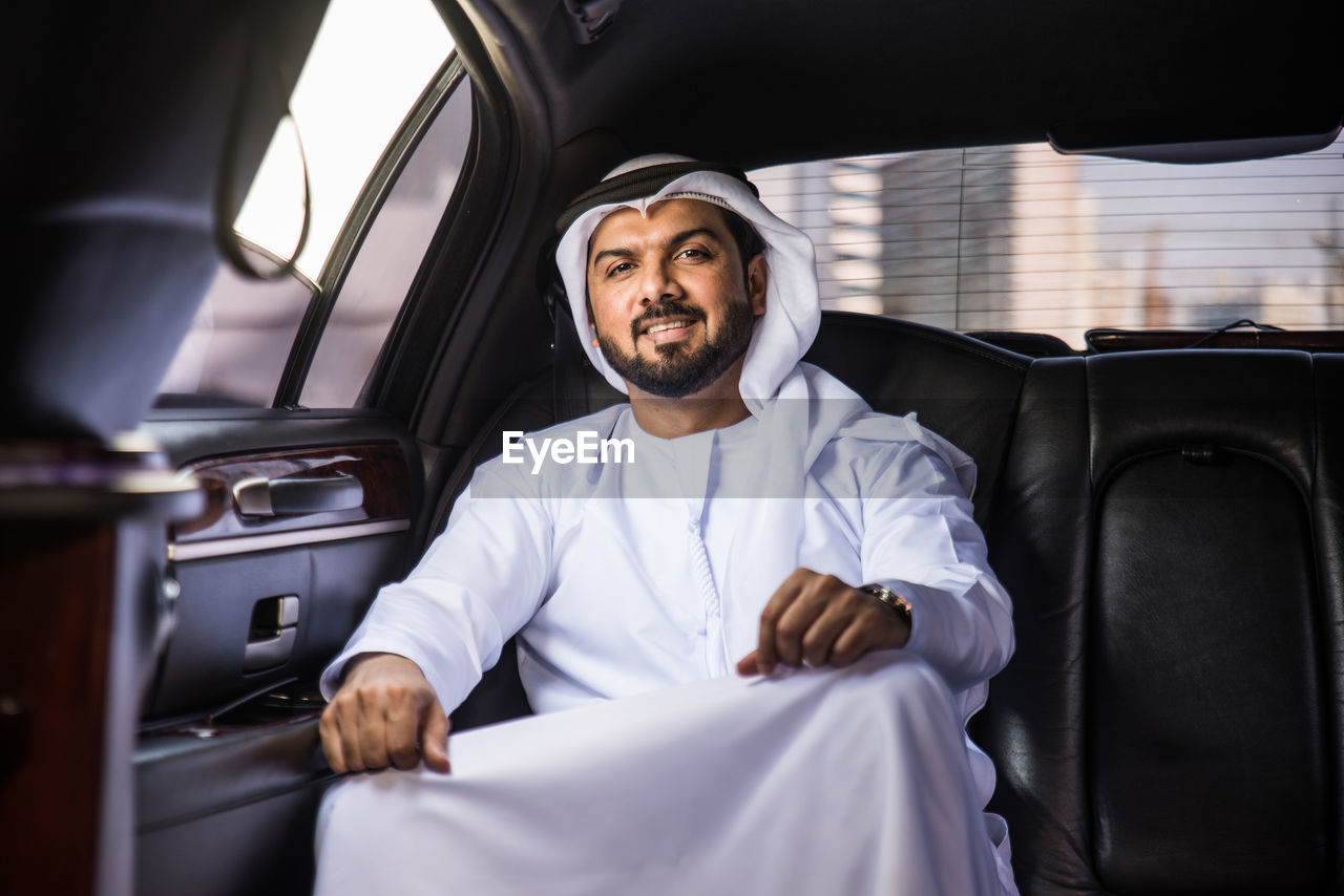 FULL LENGTH OF MAN SITTING ON CAR